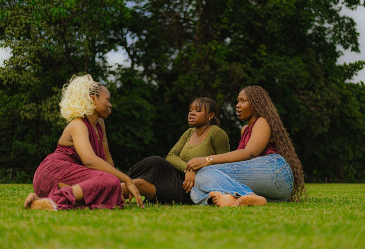 A group of women enjoying a casual chat on the grass in an Abuja park.