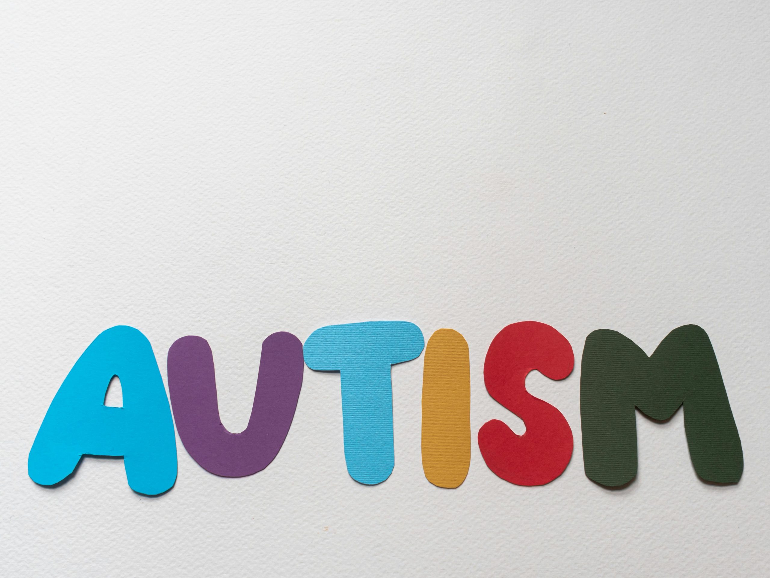 Vibrant cutout letters spelling 'AUTISM' on a white background symbolizing autism awareness.
